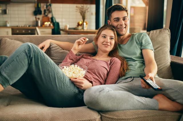 Casal no sofá com pipoca assistindo a um filme