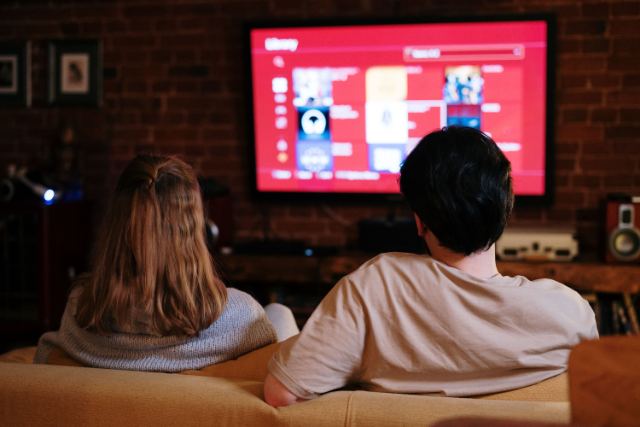 Casal no sofá assistindo a uma série na TV da sala